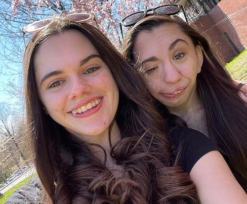 Two young women smiling taking a selfie wearing sunglasses on their head